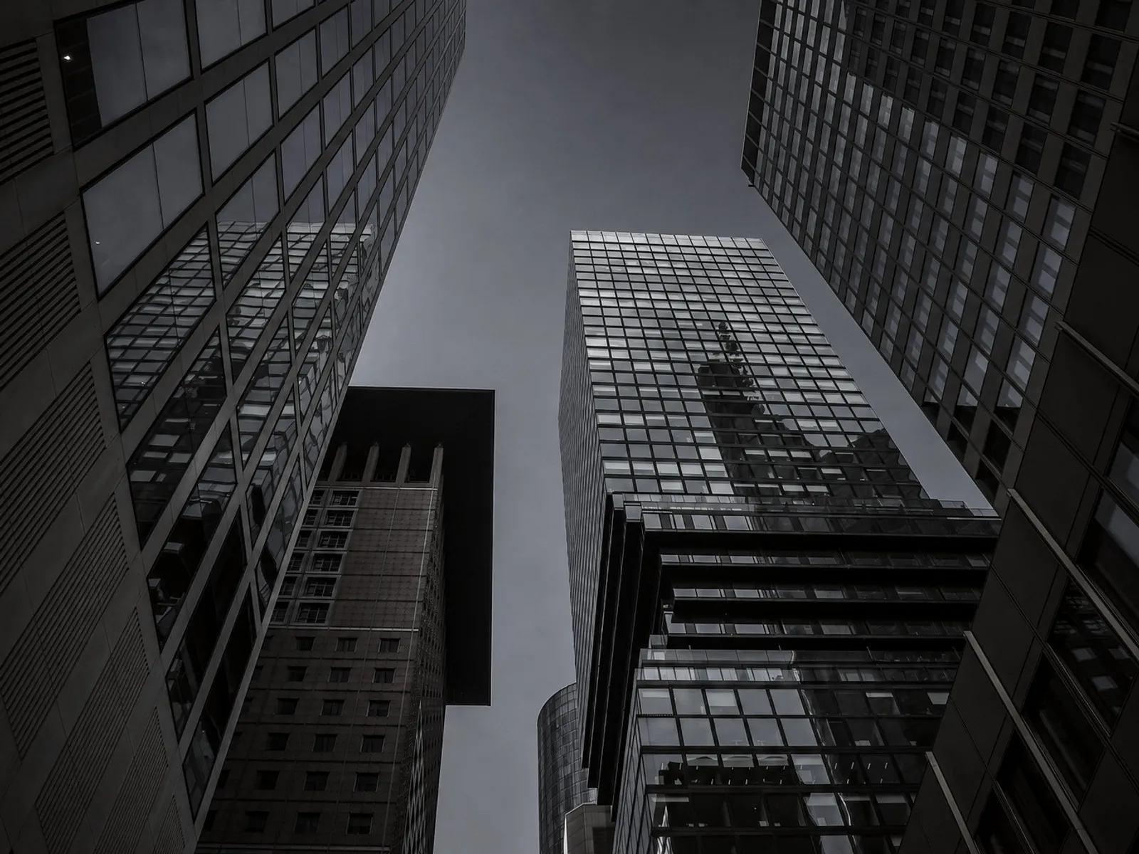 Looking up between several office towers with glass facades.